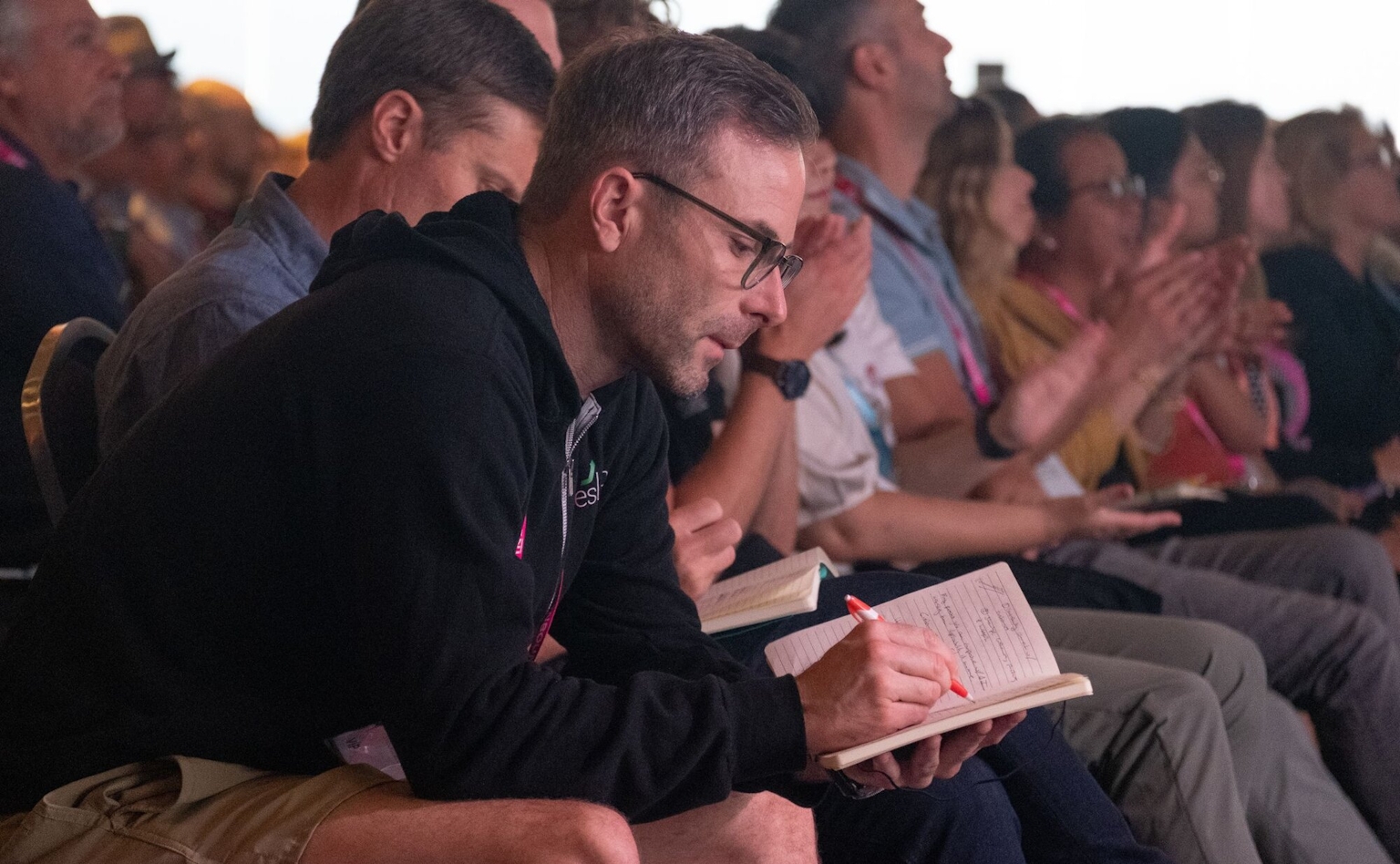 A person in a crowd taking notes in a notebook.